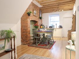 A kitchen with a dining table and brick wall at Derwen House in Llangollen