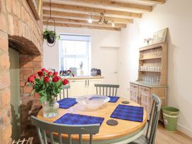 A dining room with a round table and flowers at Derwen House Llangollen