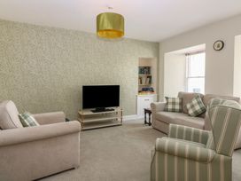 A living room with a television and bookshelf at 21A High Street, Jedburgh