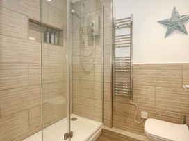 A bathroom with a shower enclosure shampoo conditioner and shower gel bottles a heated towel rail and a toilet at Sailing Home in Porthmadog