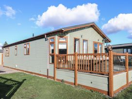 A single-story house with wooden framed windows and a wooden deck with glass panels at Stones Throw in Marston near Barkston