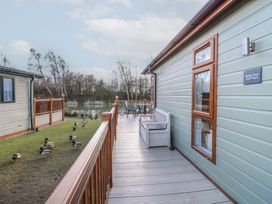 A wooden deck with a bench and table set outside a building near a pond with ducks at Stones Throw in Marston near Barkston