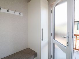 A small entryway with a bench, wall hooks, a tall white cabinet, and a frosted glass door at Stones Throw in Marston near Barkston