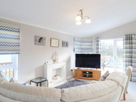 A living room with a large sofa a television on a wooden stand and chevron patterned curtains at Stones Throw Marston near Barkston