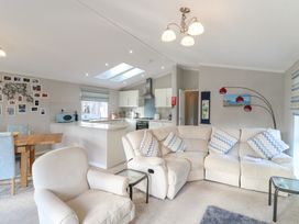 An open living room and kitchen with a beige sofa and armchair a wooden dining table and light blue chairs at Stones Throw in Marston near Barkston