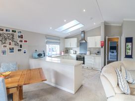 A kitchen with white cabinets and a skylight next to a wooden dining table and a beige sofa at Stones Throw Marston near Barkston