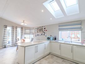 A kitchen and dining area with white cabinets and chevron patterned curtains and blinds at Stones Throw in Marston near Barkston