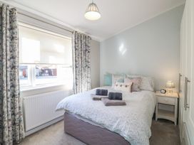 A bedroom with a double bed a bedside table and floral curtains at Stones Throw Marston near Barkston