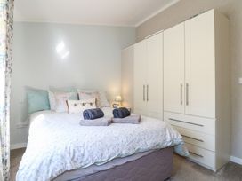 A bedroom with a bed featuring multiple pillows and towels on it next to a wardrobe at Stones Throw in Marston near Barkston