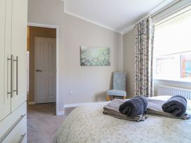 A bedroom with a bed folded towels on the bed a chair near a window and a wardrobe at Stones Throw in Marston near Barkston