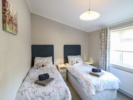 A bedroom with two single beds with bedside tables and a window with curtains at Stones Throw in Marston near Barkston