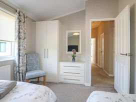 A bedroom with a chair a wardrobe a chest of drawers with a mirror and an open door at Stones Throw in Marston near Barkston