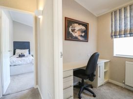 A small room with a desk and chair next to a window and a bedroom with a bed visible through an open door at Stones Throw Marston near Barkston