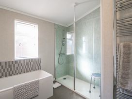 A bathroom with a bathtub a shower enclosure with a stool and a towel rail at Stones Throw in Marston near Barkston