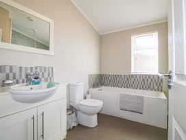 A bathroom with a sink vanity cabinet a toilet and a bathtub with a window at Stones Throw in Marston near Barkston