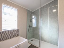 A bathroom with a bathtub under a window and a glass shower enclosure in a bathroom at Stones Throw in Marston near Barkston