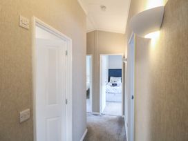A hallway with beige walls and carpet leading to bedrooms with white doors at Stones Throw in Marston near Barkston