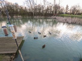 A pond with ducks swimming and bird feeders near a wooden deck at Stones Throw in Marston near Barkston