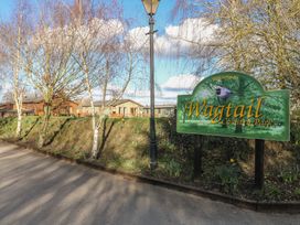 A road with a lamppost and a sign for Wagtail Country Park with trees and houses in the background