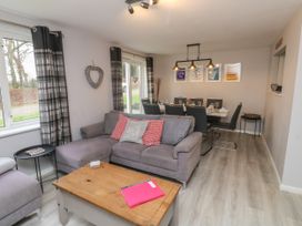 A living room with a gray sofa and coffee table next to a dining area with a table and chairs at Lewis Lodge in St Ann's Chapel
