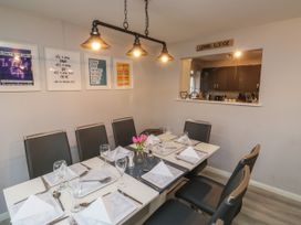 A dining room with a set table and six chairs by a window to the kitchen at Lewis Lodge in St Ann's Chapel