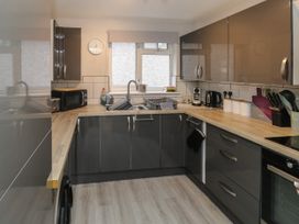 A kitchen with grey cabinets wooden countertops a window with a blind and various appliances at Lewis Lodge in St Ann's Chapel