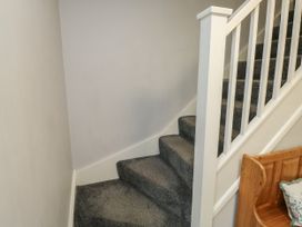 A carpeted staircase with white railing and a wooden bench with a cushion at Lewis Lodge in St Ann's Chapel