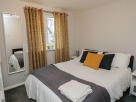 A bedroom with a bed pillows and folded towels next to a window with patterned curtains at Lewis Lodge in St Anns Chapel
