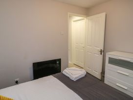 A bedroom with a bed, folded towels on the bed, a white dresser, and an open door at Lewis Lodge in St Ann's Chapel