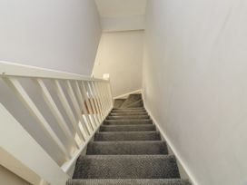A staircase with gray carpet and white railing in a residential interior at Lewis Lodge in St Ann's Chapel