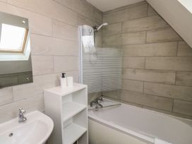 A bathroom with a bathtub shower combo a white sink a mirror and a storage shelf at Lewis Lodge in St Ann's Chapel