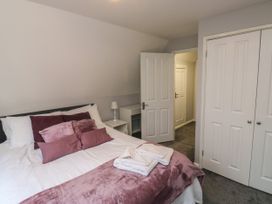 A bedroom with a bed white and pink bedding pillows a bedside table with lamp an open door and a closet with white doors at Lewis Lodge in St Ann's Chapel