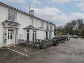 An exterior view of a white building with outdoor seating and parked cars at Lewis Lodge in St Ann's Chapel