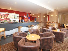 A bar area with stools high tables and brown armchairs around wooden tables at Lewis Lodge in St Ann's Chapel