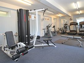 A gym room with exercise machines including a cable machine, stationary bikes, treadmills, and benches at Lewis Lodge in St Ann's Chapel
