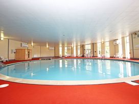 An indoor swimming pool with red flooring and chairs along the walls at Lewis Lodge in St Ann's Chapel