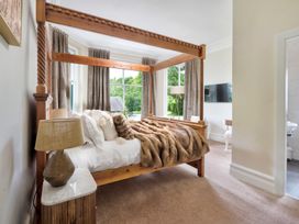 A bedroom with a wooden bed and a television in Rosemount Boutique Windermere