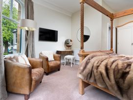 A bedroom with a four-poster bed and two chairs at Rosemount Boutique in Windermere