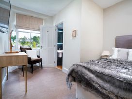 A bedroom with a bed, chair, and mirror at Rosemount Boutique in Windermere