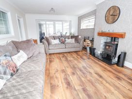 A living room with two sofas a fireplace a wooden clock and wooden floor at Greenacres in Towyn