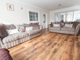 A living room with two sofas with cushions and wooden flooring at Greenacres in Towyn