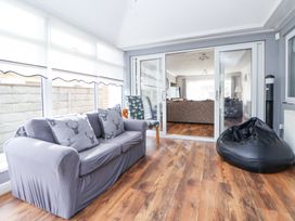 A seating area with a sofa and bean bag on wooden floor at Greenacres in Towyn