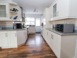 A kitchen with white cabinets a microwave on the counter and wooden flooring at Greenacres in Towyn