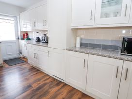 A kitchen with white cabinets wooden floor a blender toaster microwave and a door at Greenacres in Towyn
