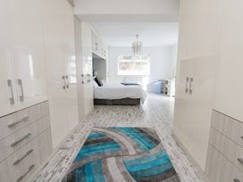 A bedroom with wardrobes on both sides a bed at the end and a rug on the floor at Greenacres in Towyn