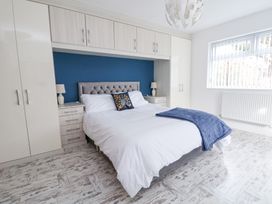 A bedroom with a double bed white bedding blue blanket built in wardrobe and window blinds at Greenacres in Towyn