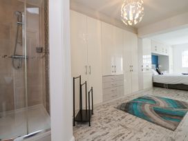 A bedroom with a large white wardrobe a bed a blue and gray rug and a shower at Greenacres in Towyn