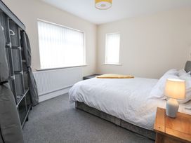 A bedroom with a bed white bedding bedside table lamp and fabric wardrobe at Greenacres in Towyn