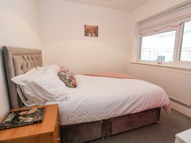 A bedroom with a bed a nightstand with a book and a window at Greenacres in Towyn