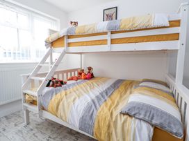 A bedroom with a white bunk bed with yellow and gray bedding and stuffed animals at Greenacres in Towyn